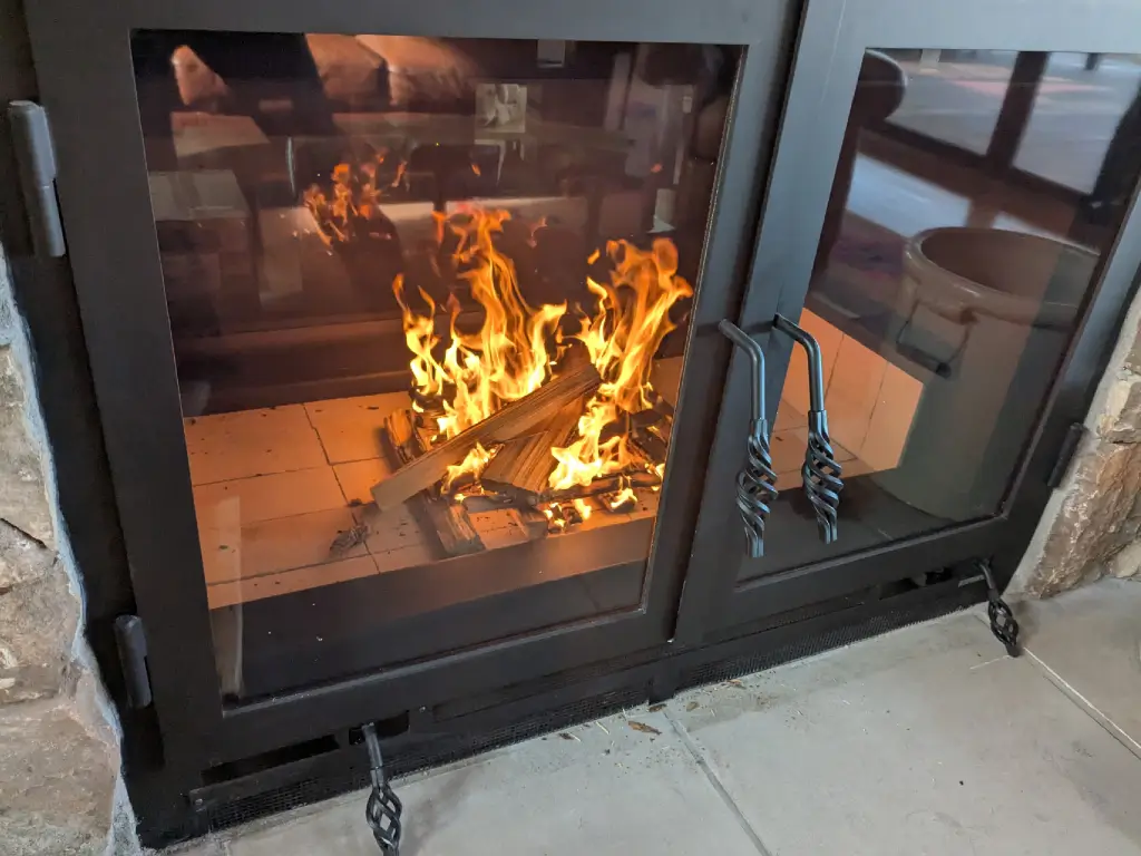 Burning logs viewed through the glass doors of an Acucraft Hearthroom 44 see-through wood fireplace.