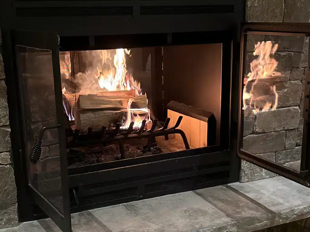 Acucraft Hearthroom 44 see-through wood fireplace with an open door showing a steady wood fire.