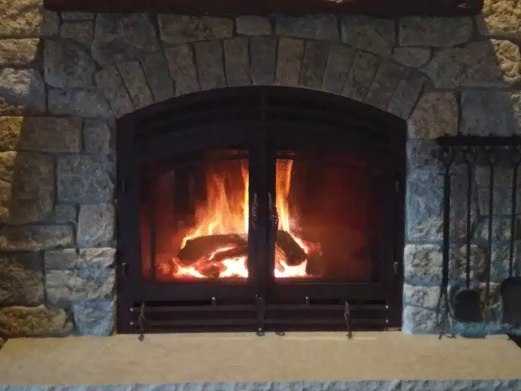 Glowing fire behind the closed arched doors of an Acucraft Hearthroom 44 single-sided fireplace.