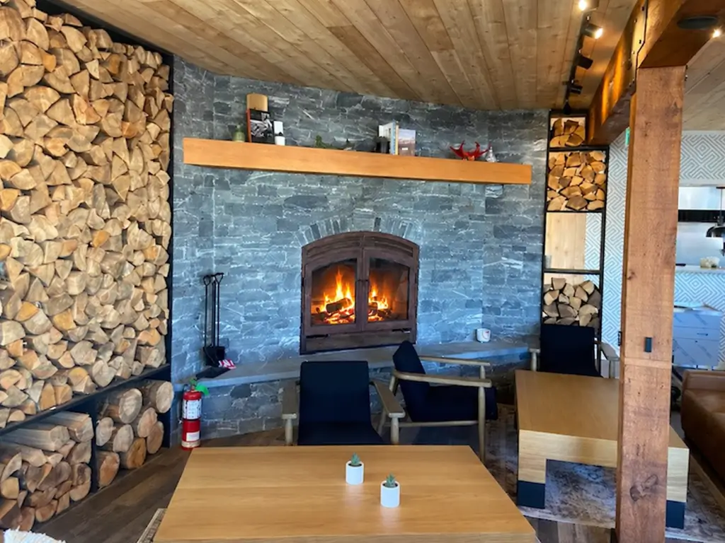 Acucraft wood fireplace beside a built-in firewood stack in a lodge